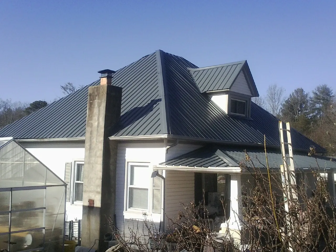 Dark blue standing seam metal roof on a white farmhouse with dormer — Slate & Tile Roof Repair by Roofing Brothers in Saugatuck