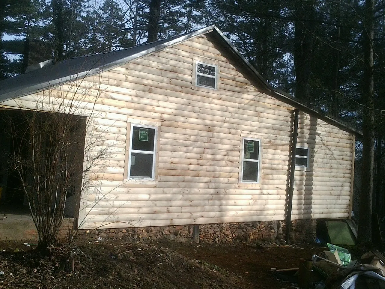 New log siding and dark metal roofing on a gable end in Saugatuck