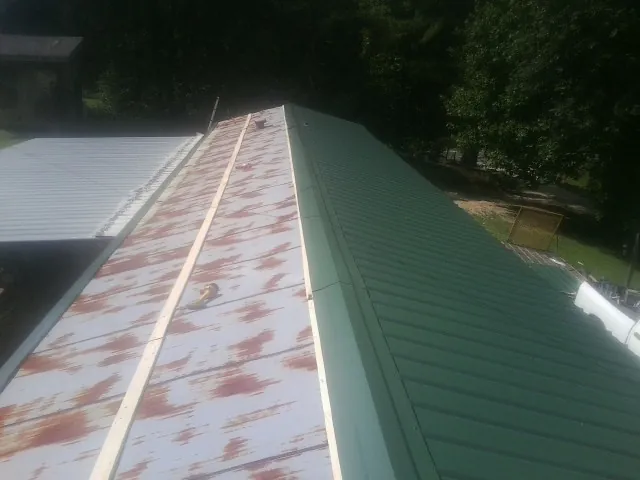 Old rusted panels beside newly installed green metal roofing — Wind Damage Roof Repair by Roofing Brothers in Saugatuck