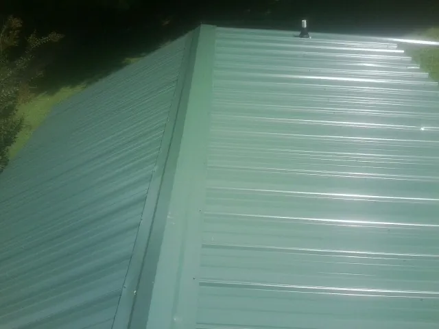 New green metal panels meeting at the ridge of a roof — Flat Roof Repair work by our crew in Saugatuck