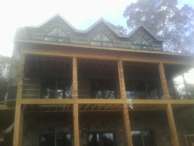 Dormers and porch framing on a large log home under construction — Roof Coating work by our crew in Saugatuck