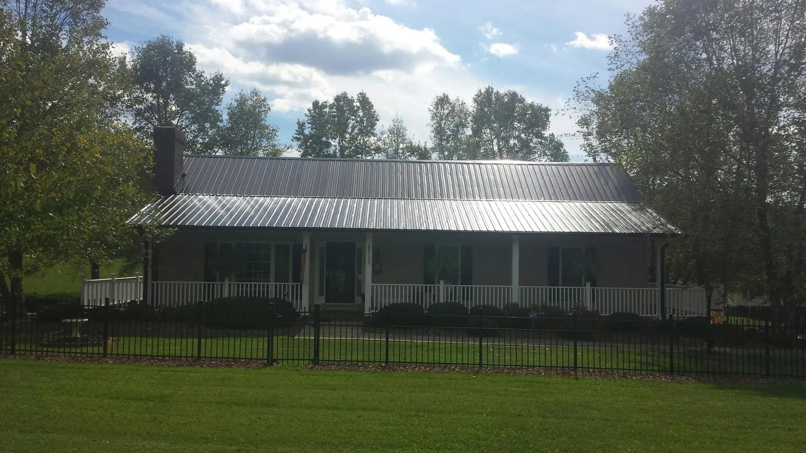 Gray metal roof on a brick ranch with a full width front porch — Gutter Guard Installation work by our crew in Saugatuck