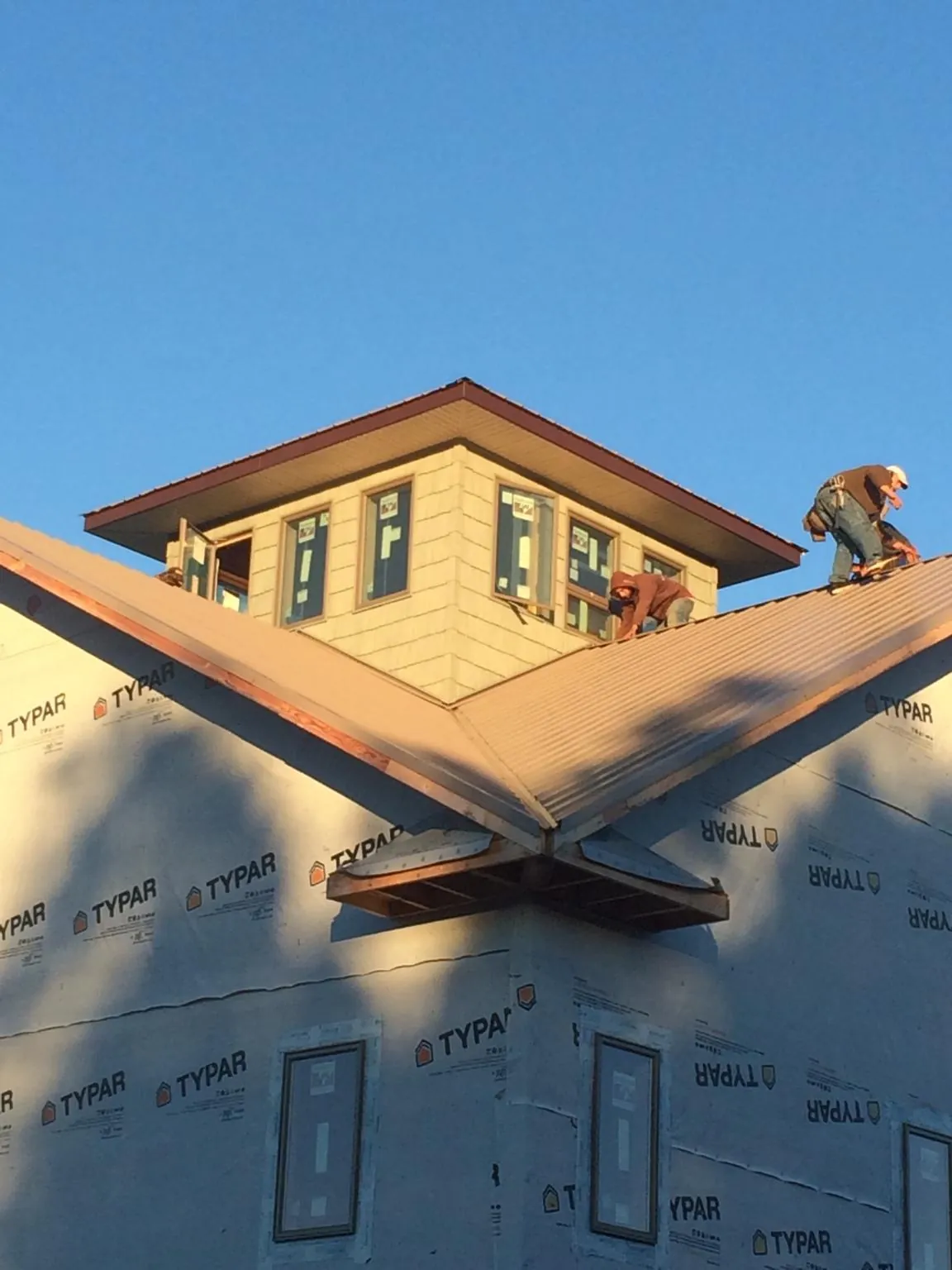 Roofers working around a rooftop cupola on a new metal roof at sunset — Roof Waterproofing in Saugatuck by Roofing Brothers
